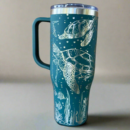 Teal tumbler with white sea turtle design on a beige background