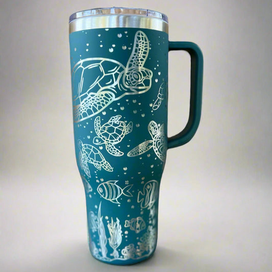 Teal travel mug with white sea turtle and fish design on a light gray background