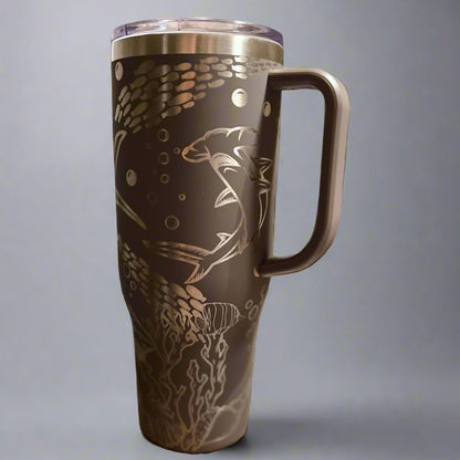 Brown travel mug with shark and fish design on a gray background